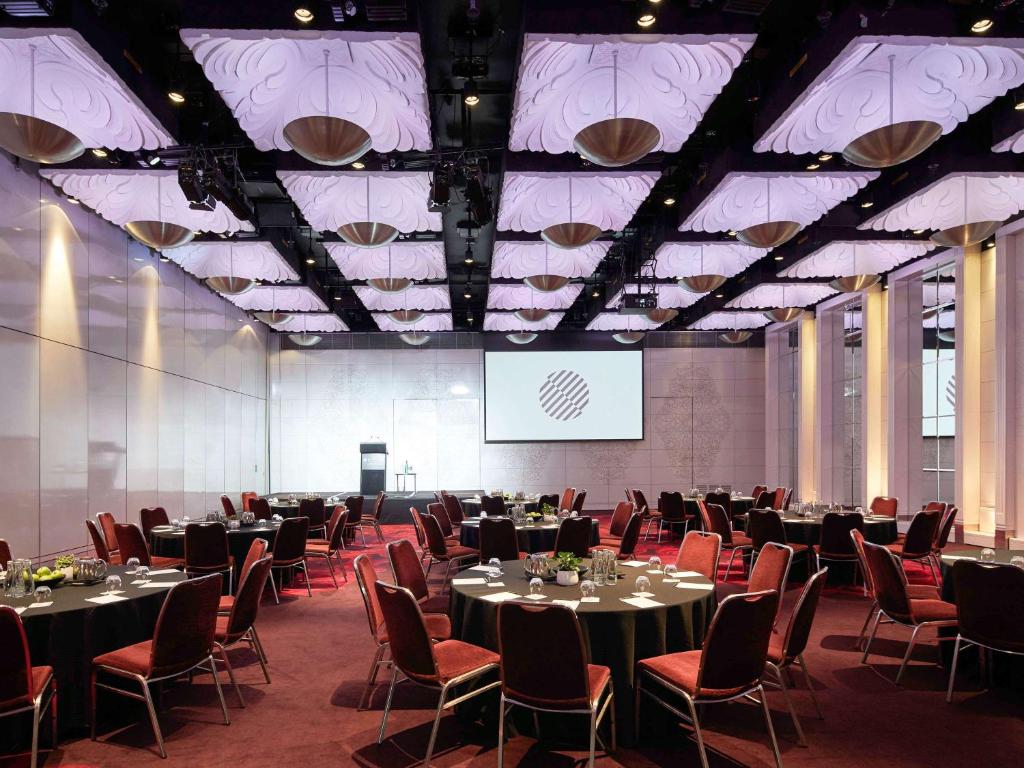 Ballroom 3 at Pullman Melbourne On The Park: A large function room set up with chairs around a number of round tables. A large screen is displayed on the back wall.